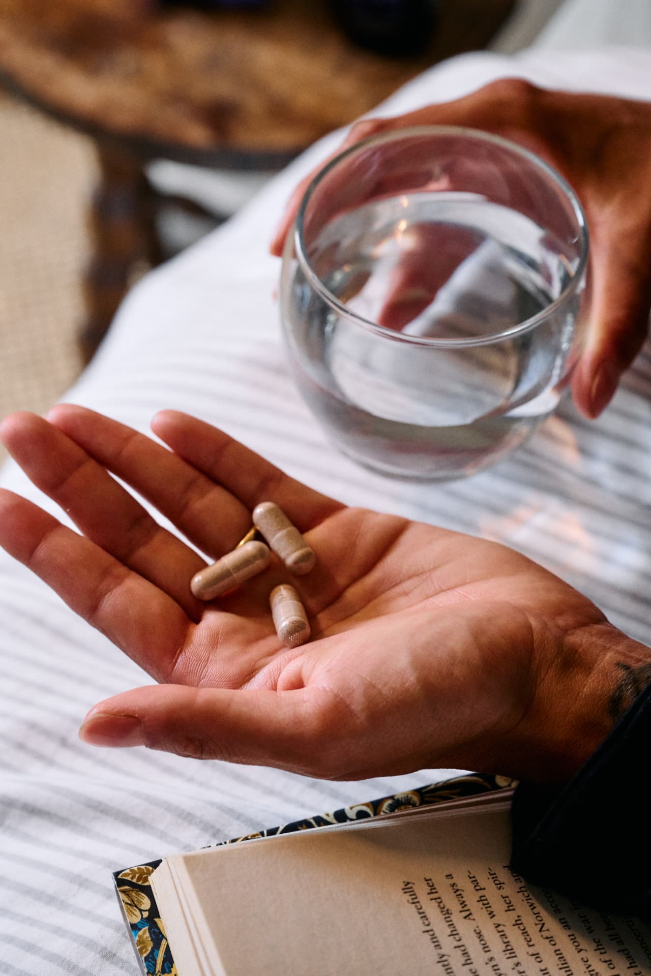 DREAM capsules in a palm with a glass of water and a book