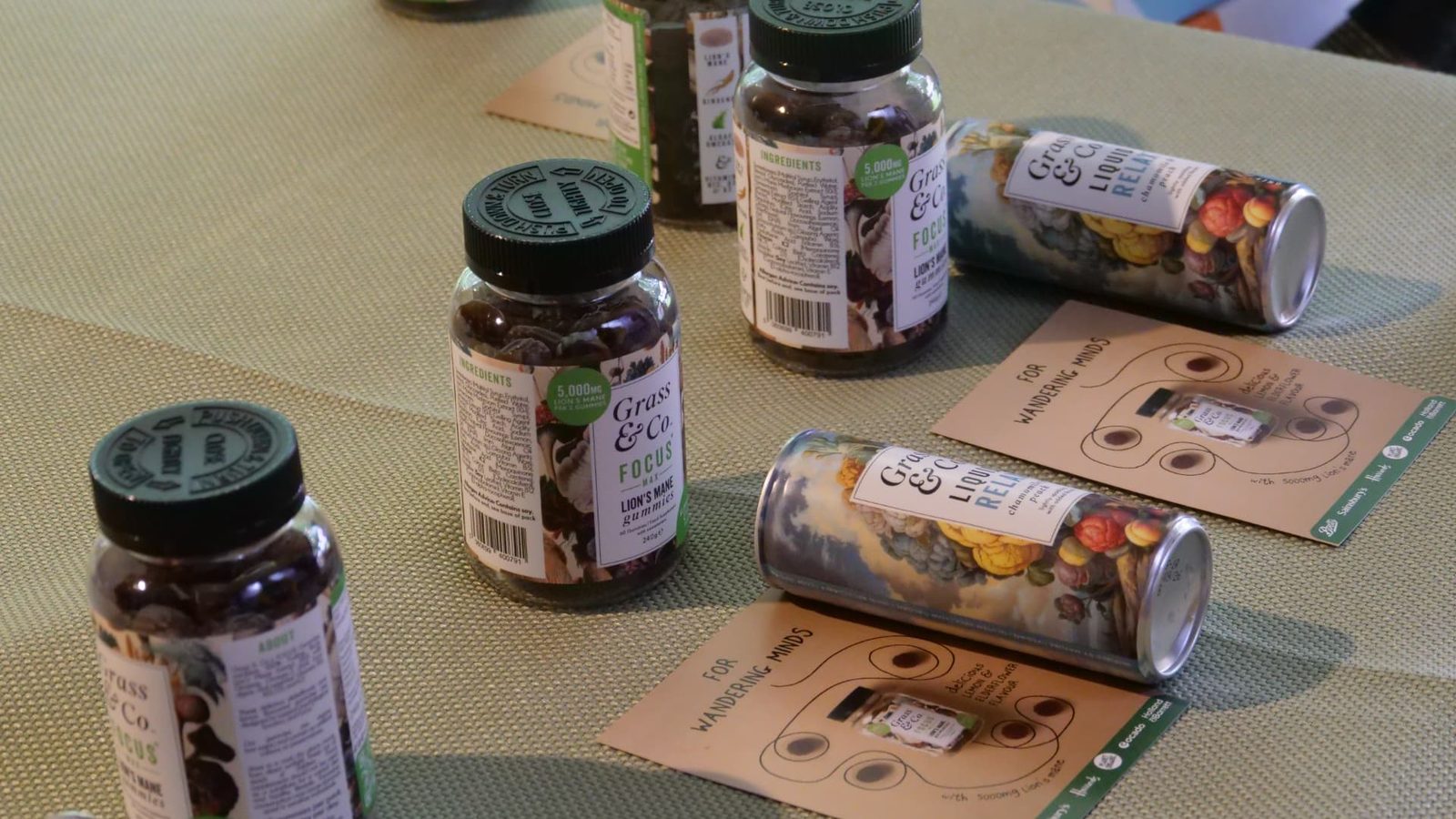 Grass & Co. FOCUS jars, FOCUS MAX gummies and Liquid RELAX cans laid out on the workshop table